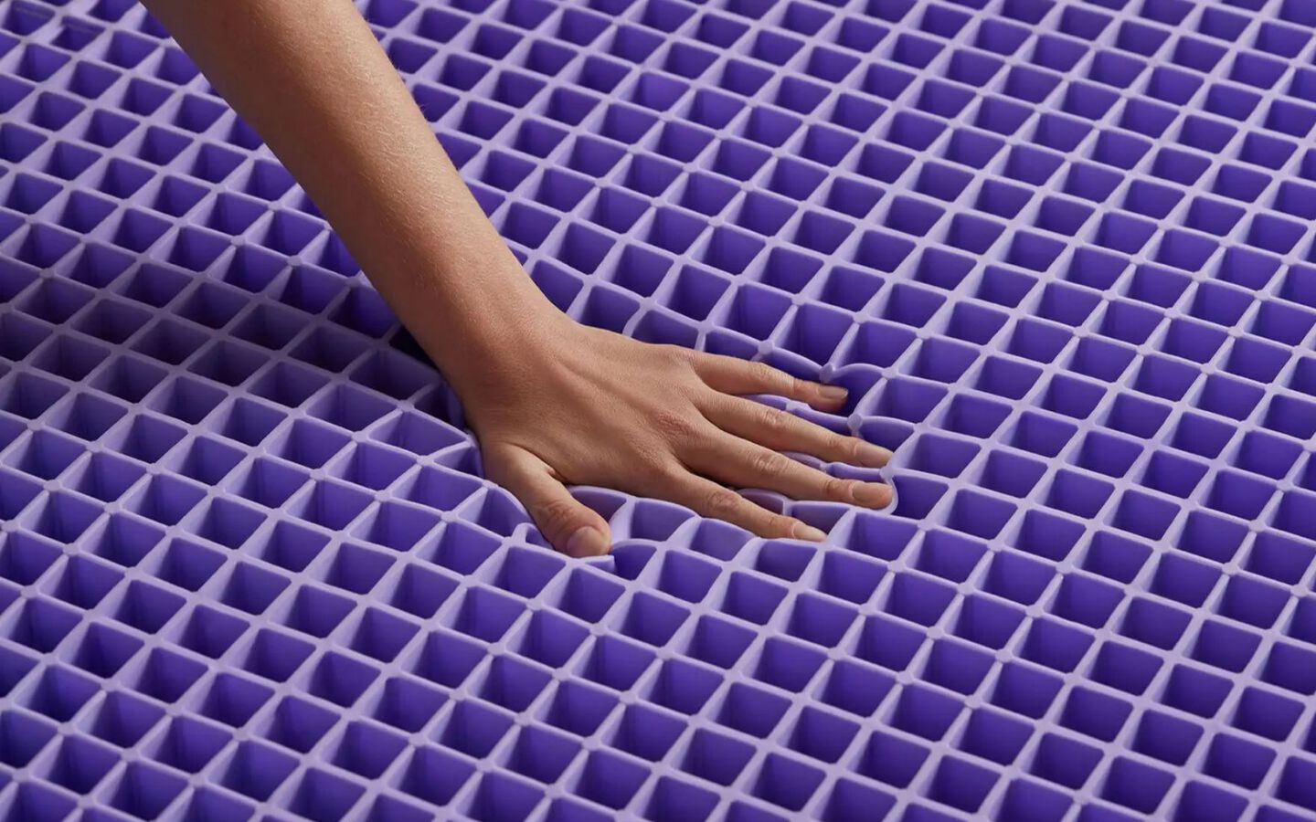Hand pushing down on the Purple mattress matrix