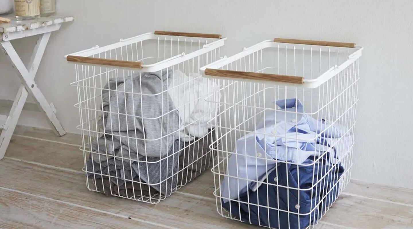 Two white wired laundry hampers filled with clothing