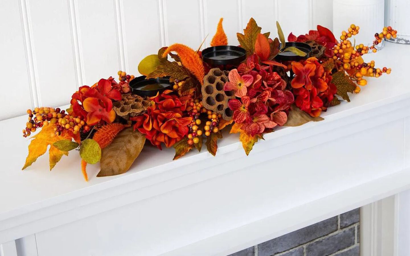 White fireplace mantel with decorative orange, yellow, and red leaf candle holder