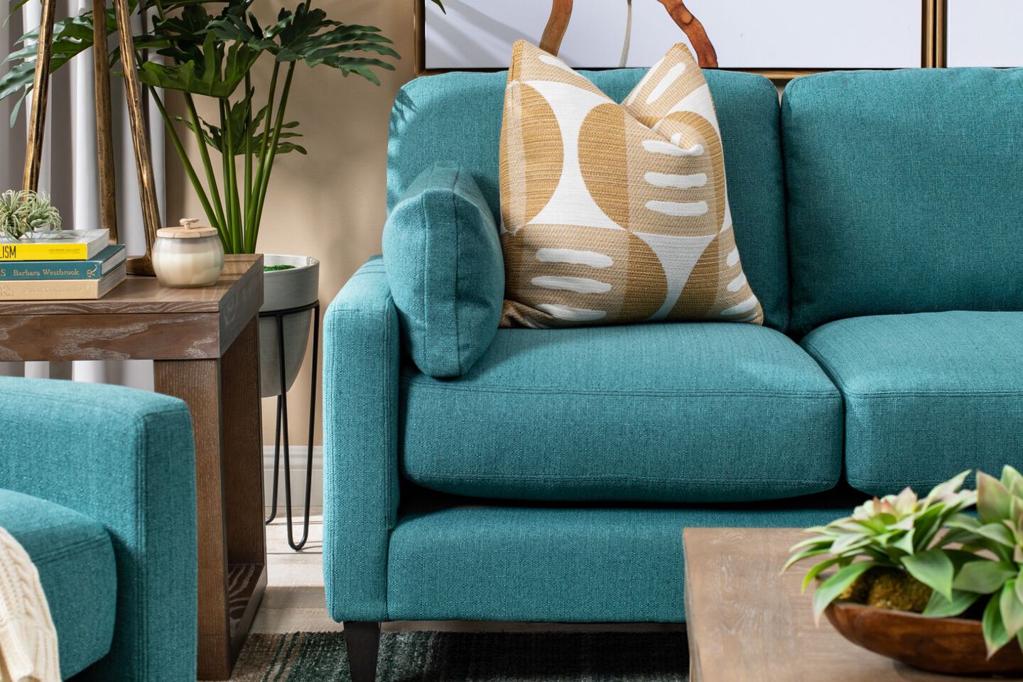 Living room with side table, coffee table, and teal blue couch with a yellow pillow