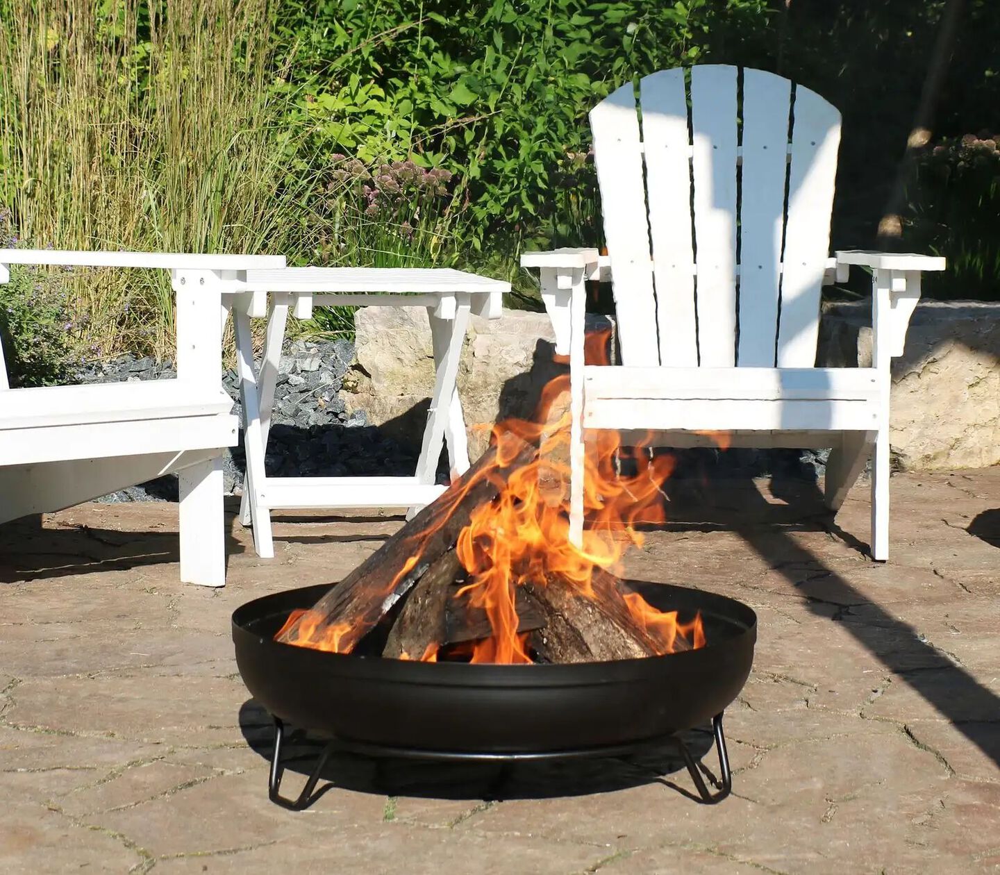 Outdoor fire pitting with fire burning sitting in front of white patio chair set