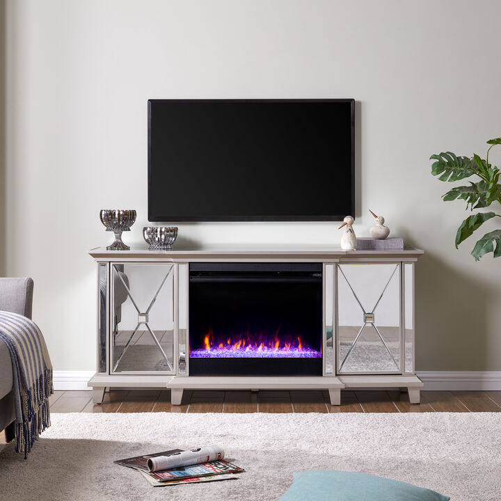 Mirrored electric fireplace. Silver finish pairs with a mirrored frame. Shimmering faux crystal adds ambiance with flickering LED flames, alternating colors, and lifelike embers.