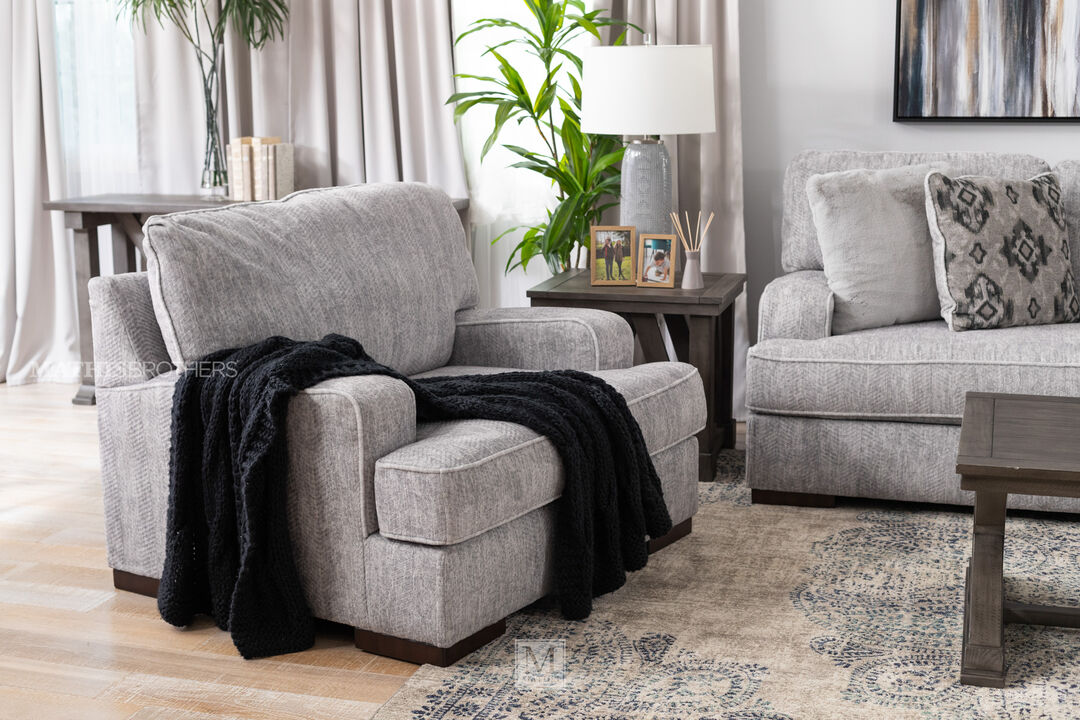 Mercado Oversized Chair in pewter in a living room setting with a black throw places across the seat and arm of the chair. 